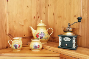 EIn historisches Kaffeegeschirr neben ein manuellen Kaffeemühle.
